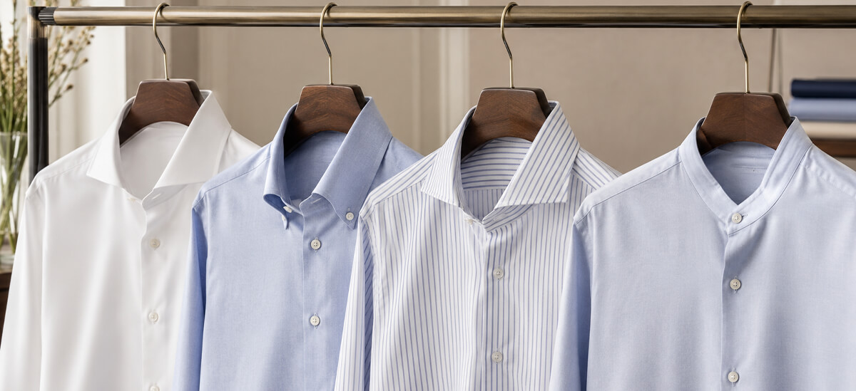 Guida ai tipi di collo delle camicie uomo Quattro camicie uomo con colletti differenti appese su grucce